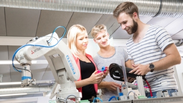 Foundation year engineering students work on a piece of machinery in a lab.