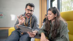 Two students looking at a tablet screen discussing what is on there.