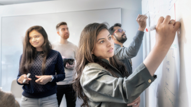 Pre-Masters business students working at a whiteboard in class.