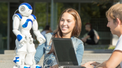 Two students are working outside on a robot