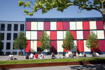 Exterior of our campus building with white and red blinds visible.