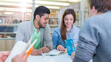 Three students study in a breakout room in the library