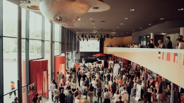 SRH Heidelberg campus building interior filled with students attending an event.