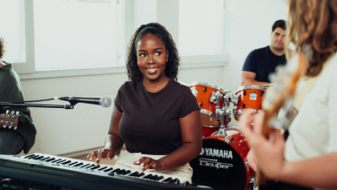 SRH International creative studies student at her piano looking at her bandmate