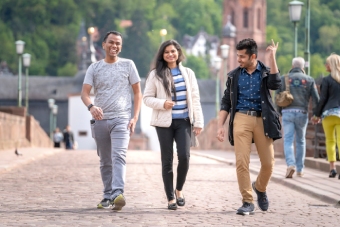 Three international students visiting the historic Old Bridge in Heidelberg
